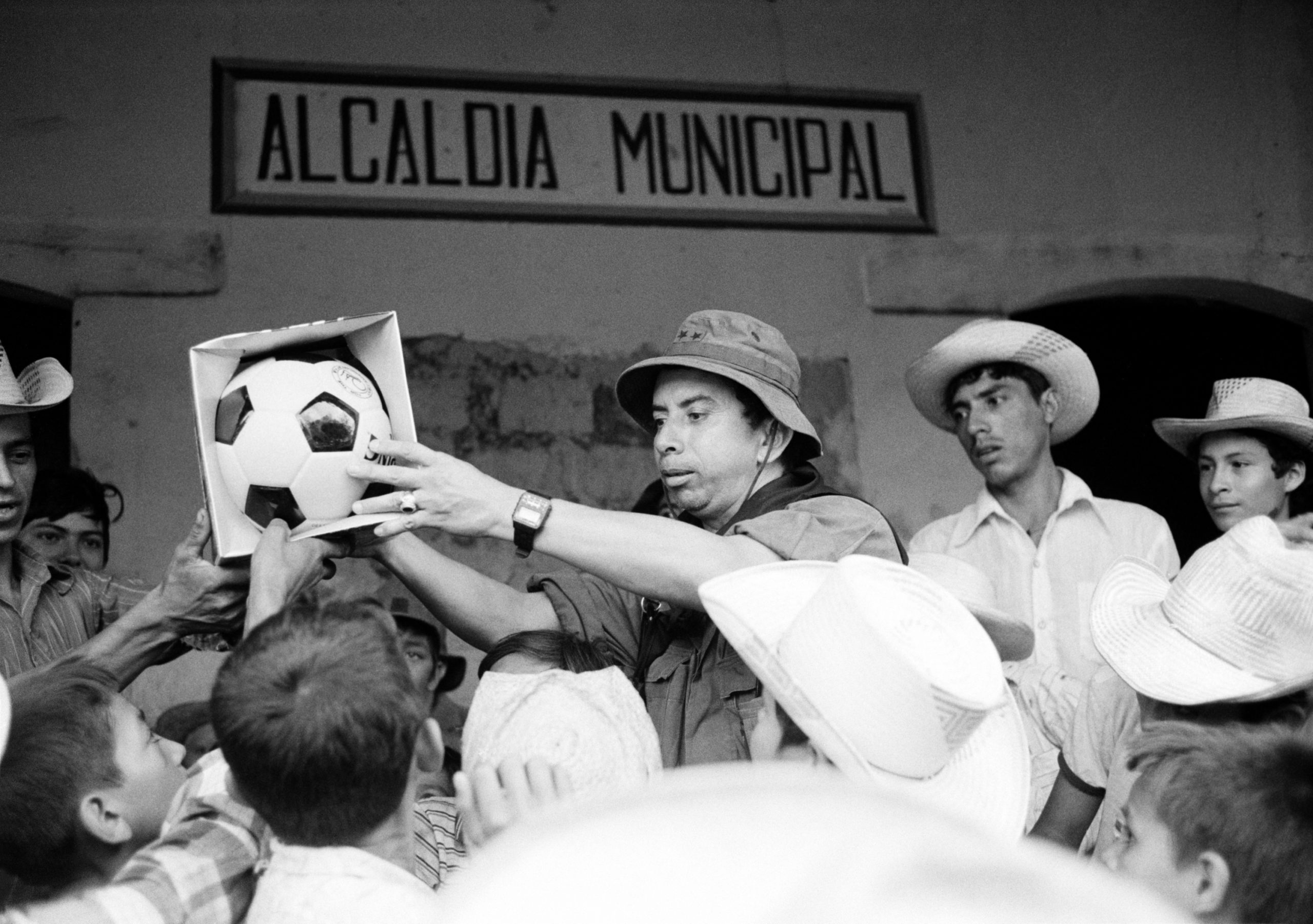 The Atlacatl Battalion commander, Lieutenant Colonel Domingo Monterrosa, hands a new soccer ball to local children in Joateca, Morazán department, El Salvador, October 22, 1984. (Photo by Robert Nickelsberg/Getty Images)