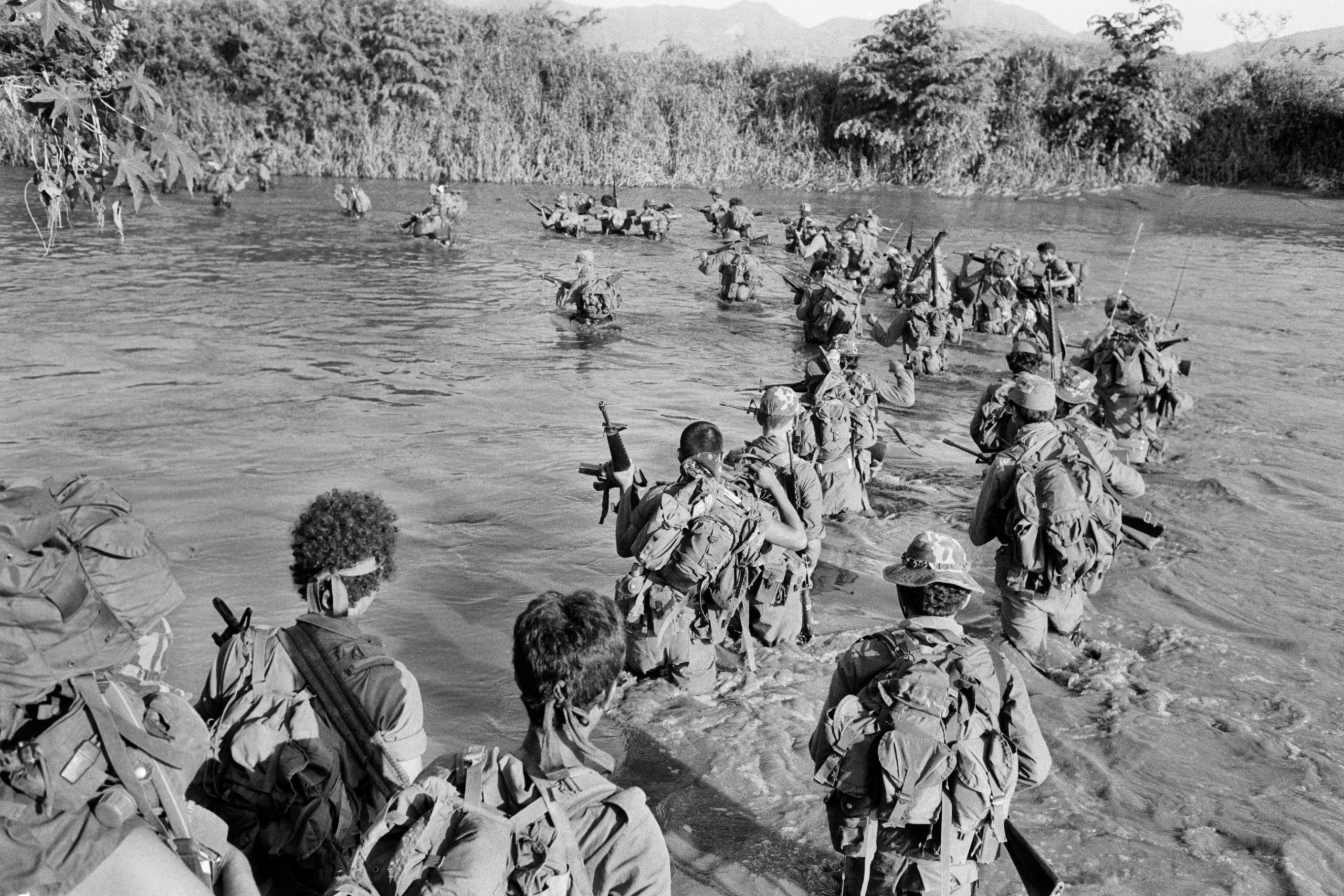 Salvadoran members of the Atlacatl battalion cross a river during a military operation in San Miguel department, El Salvador, circa late August to early September 1983. The Atlacatl Battalion was trained at Ft. Bragg in the United States by U.S. Special Forces as the first Salvadoran rapid response counterinsurgency battalion and was implicated in some of the most infamous human rights violations of the twelve-year armed conflict.